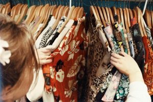 Photograph of someone browsing a selection of shirts in a shop.
